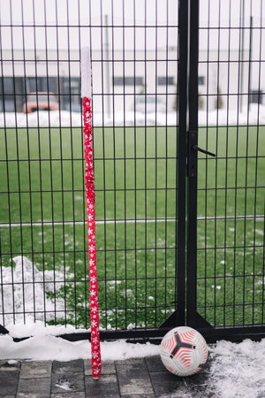 Soccer ball leaning against a candy cane staff near a fenced field, blending holiday spirit with...