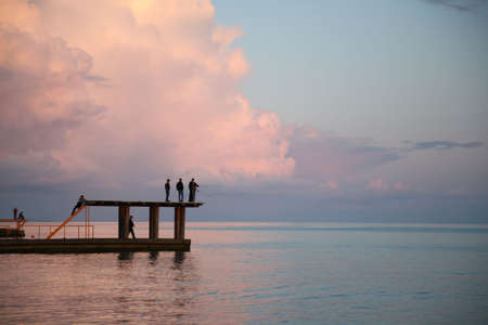 Fishermen on a decline fish from a pier in the seaの写真素材
