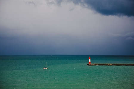 The small yacht comes into a bay before an approaching thunder-storm and a stormの写真素材