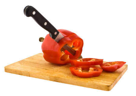 The knife cuts a fruit of red pepper on a chopping board on a white backgroundの写真素材