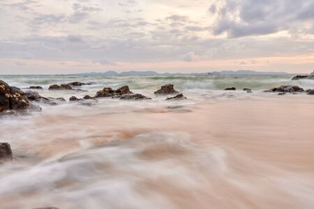a wavy sea with rocks near a beach.の写真素材