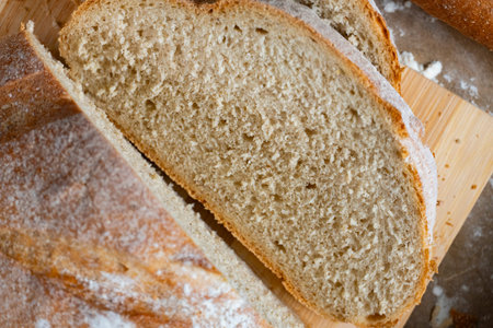 Two artisan bread loaves rest on parchment with wheat stalks and rolling pin, creating a cozy...