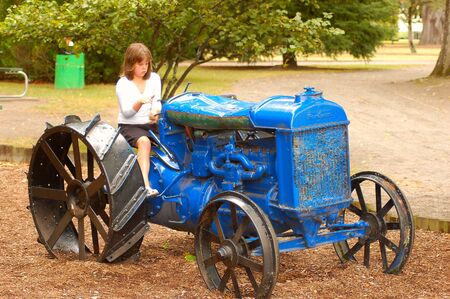 young girl on old farm tractorの写真素材