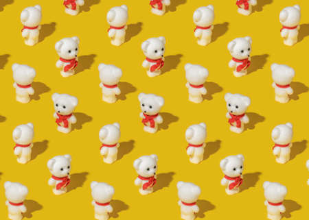 Creative pattern made of white teddy bear with red scarf on yellow background. Isometric view. Bright light.の写真素材