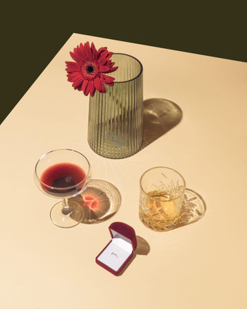 Vintage Valentines day scene with engagement ring box, crystal whiskey and vine glasses and red...
