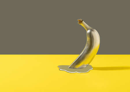 Minimal retro futurism background with halved banana and silver liquid against gray and yellow.の写真素材