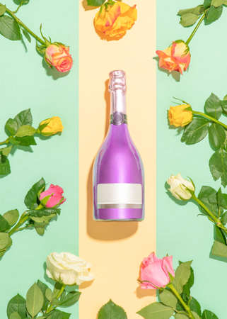 Vibrant spring party flat lay composition made of violet champagne bottle and colorful rose flowers on duo tone green table.の写真素材