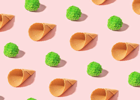 Creative summer pattern with green ice cream scoops and cones  on sunny pink background. Minimal summer food concept.の写真素材