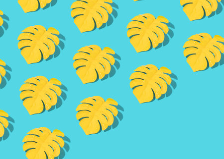 Creative summer pattern made of yellow monstera leaves on bright bastel blue. Minimal tropical...