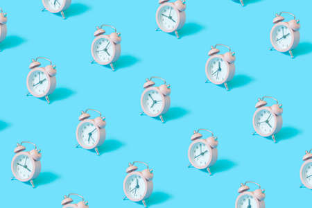 Trendy pattern with red retro alarm clock on pastel blue background.の写真素材