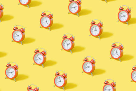 Trendy pattern with beige retro alarm clock on pastel yellow background.の写真素材
