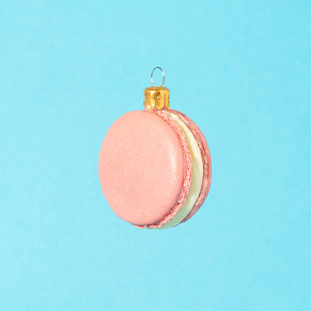 Minimal composition with tasty pink macaron on bright blue background. Sweet Christmas decoration.の写真素材