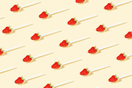 Trendy pattern with fresh strawberry on white spoon against bright sandy background. Healthy diet wallpaper.の写真素材