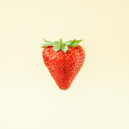 Minimal composition with fresh red strawberry against bright sandy background.の写真素材