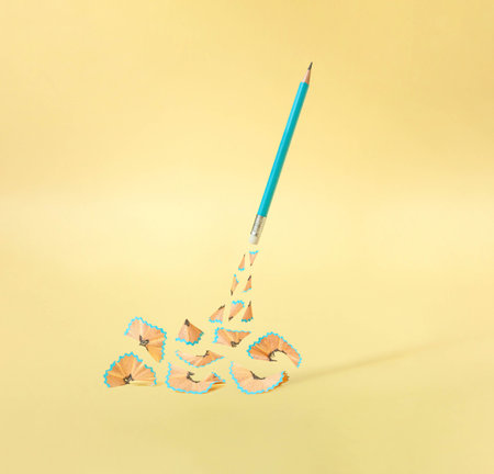 Creative composition with wooden waste from sharpened pencil against gold yellow background. Surreal knowledge concept.の写真素材