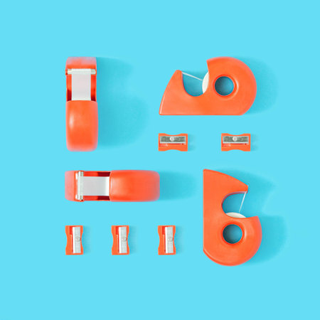 Creative flat lay with red desktop tape dispenser and pencil sharpener on pastel blue background....
