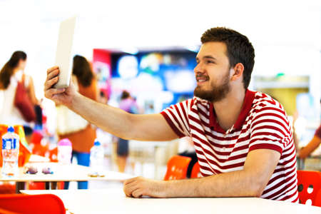 Young man is making selfie in shopping centre.の写真素材