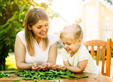Mother and daughter enjoying outhside and peeling peas off.の写真素材