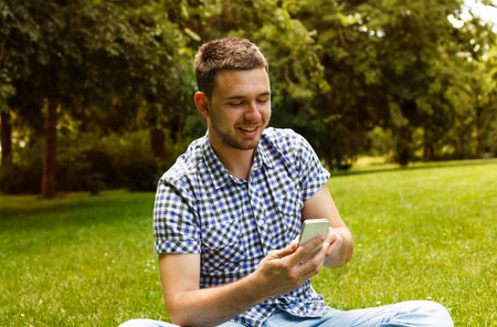 Young man is using phone in the park.の写真素材
