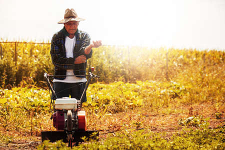 Farmer is working with cultivator machine.の写真素材