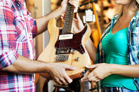 Young woman is looking for guitar in musical instruments store.Close up.の写真素材