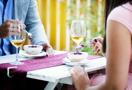 Happy couple in a restaurant eating dessert and drinking wine.の写真素材