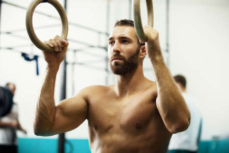 Young fit man is preparing for pulling up on gymnastic rings.の写真素材