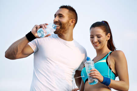 Young couple drinking water while exercising.の写真素材