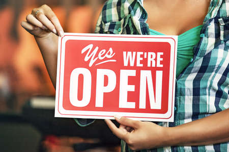 Musical intruments store. Salesperson  is showing open store sign.の写真素材