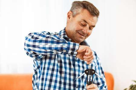 Senior man opening wine bottle. Selective focus on hand.の写真素材