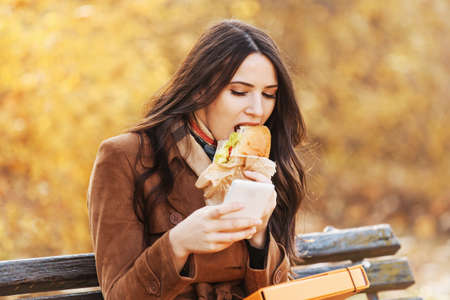 Beautiful young woman eating in the park. の写真素材