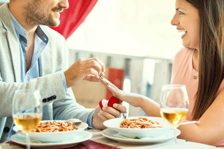 Engagement in a restaurant. Young man is giving a ring to his girlfriend.の写真素材