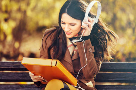 Young woman in the park using head phones. の写真素材