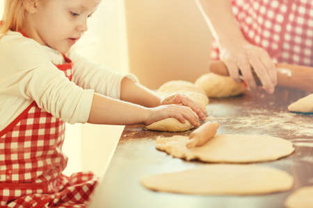 Mother and daughter in the kitchen preparing croissants to bake. の写真素材