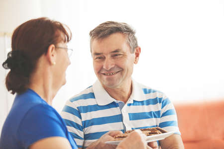 Seniors enjoying living room and eating cakes.の写真素材