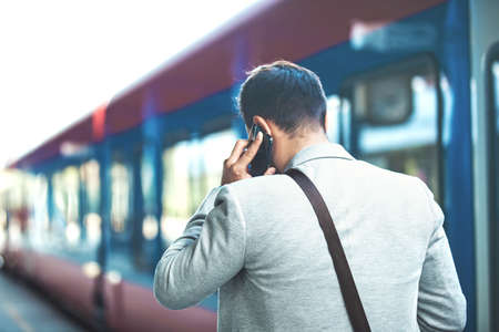 Business person is waiting for train and speaking on phone.の写真素材