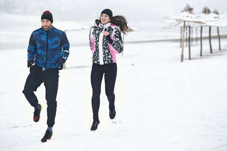 Couple running on cold winter day.の写真素材