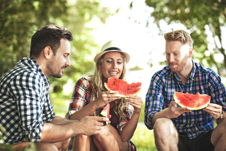 Friends enjoying nature and eating watermelon.の写真素材