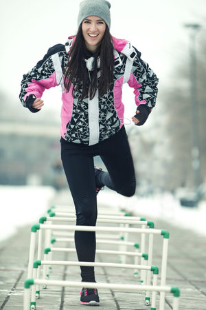 Beautiful young woman exercising outdoors. Cold winter day.の写真素材