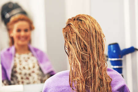 Young blonde woman enjoying hair treatment.の写真素材
