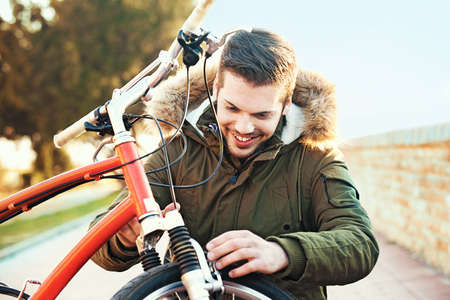 Young handsome man is checking brake on his bike.の写真素材