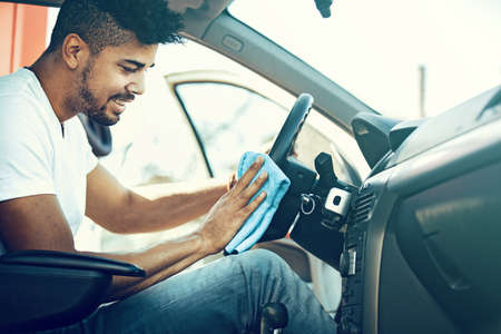 Young handsome man is cleaning car interior.の写真素材