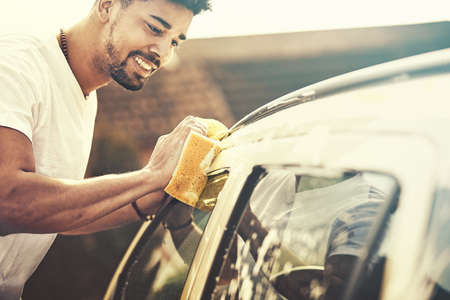 Young handsome man is washing car outdoor.の写真素材
