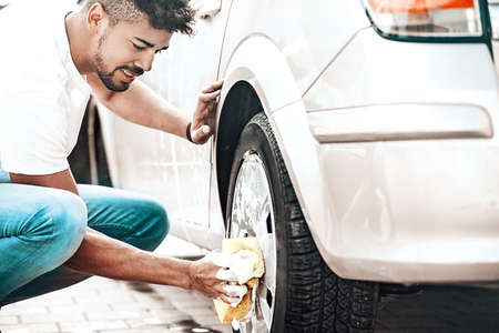 Young handsome man is washing car outdoor.の写真素材