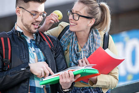 Student couple holding books and eating apple.の写真素材