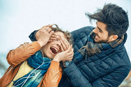 Handsome man surprising his girlfirend in the park.の写真素材