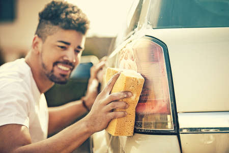 Young handsome man is washing car outdoor.の写真素材