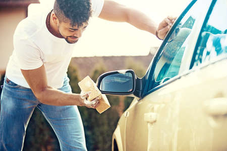 Young handsome man is washing car outdoor.の写真素材