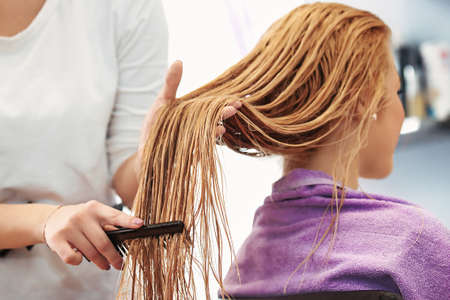 Young beautiful blonde woman enjoying hair treatment.の写真素材