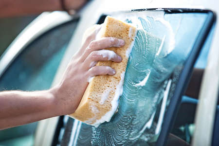 Young handsome man is washing car outdoor.の写真素材